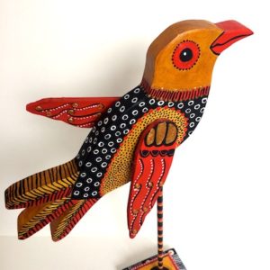Handmade wooden bird sculpture. Mounted on a wooden pole and stand. Painted in bright colors..